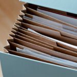 Business Case - From above of opened modern briefcase with prepared papers placed on timber table in soft focus