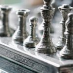 Strategy Development - Classic metal chess board with set figurines designed with carved ornaments and placed on glass table in light room
