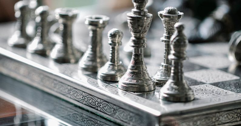 Strategy Development - Classic metal chess board with set figurines designed with carved ornaments and placed on glass table in light room