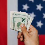 Pareto Principle - Unrecognizable male demonstrating dollars before official flag of USA on background