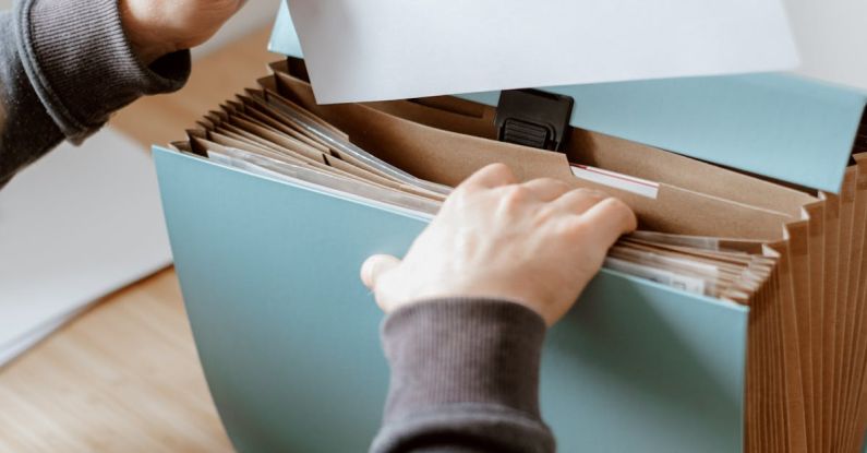 Total Quality Management - Crop anonymous male putting blank sheet of paper in case placed on wooden table