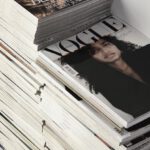 Trend Analysis - High angle many fashion magazines stacked on floor against white brick wall in studio