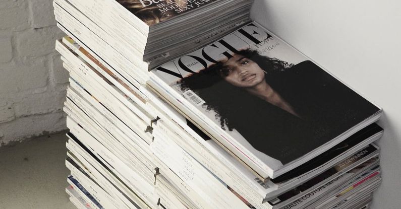 Trend Analysis - High angle many fashion magazines stacked on floor against white brick wall in studio