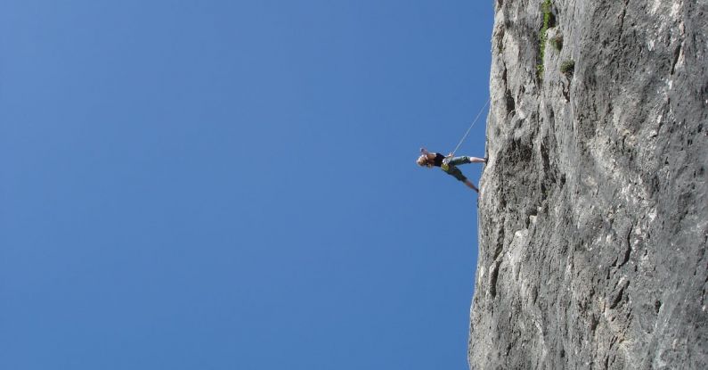 Risk - Man Standing on Rock Against Clear Blue Sky