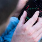 Financial Derivatives - A man is using his cell phone to look at the stock market