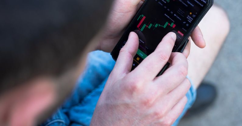 Financial Derivatives - A man is using his cell phone to look at the stock market
