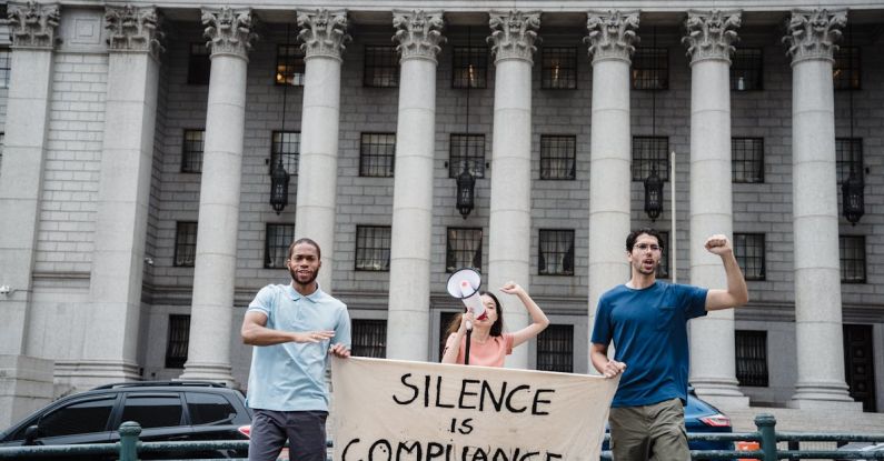 Compliance - Protesters Holding a Banner with a Slogan