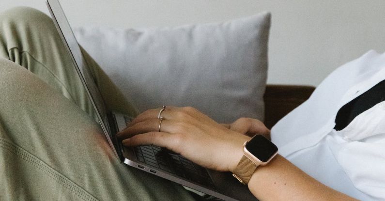 Project Casebook - Side view of crop unrecognizable female freelancer in casual clothes and smartwatch lying on comfortable sofa and working remotely on laptop
